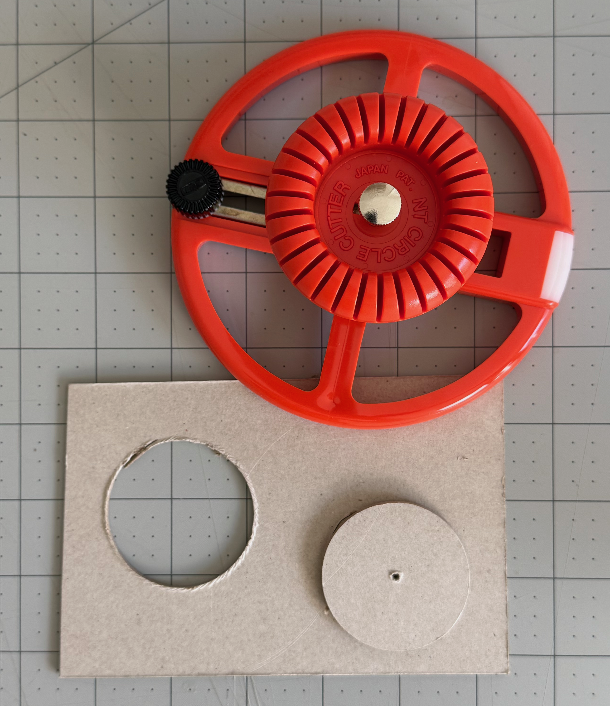 Circular cutting tool positioned above a cut chipboard circle