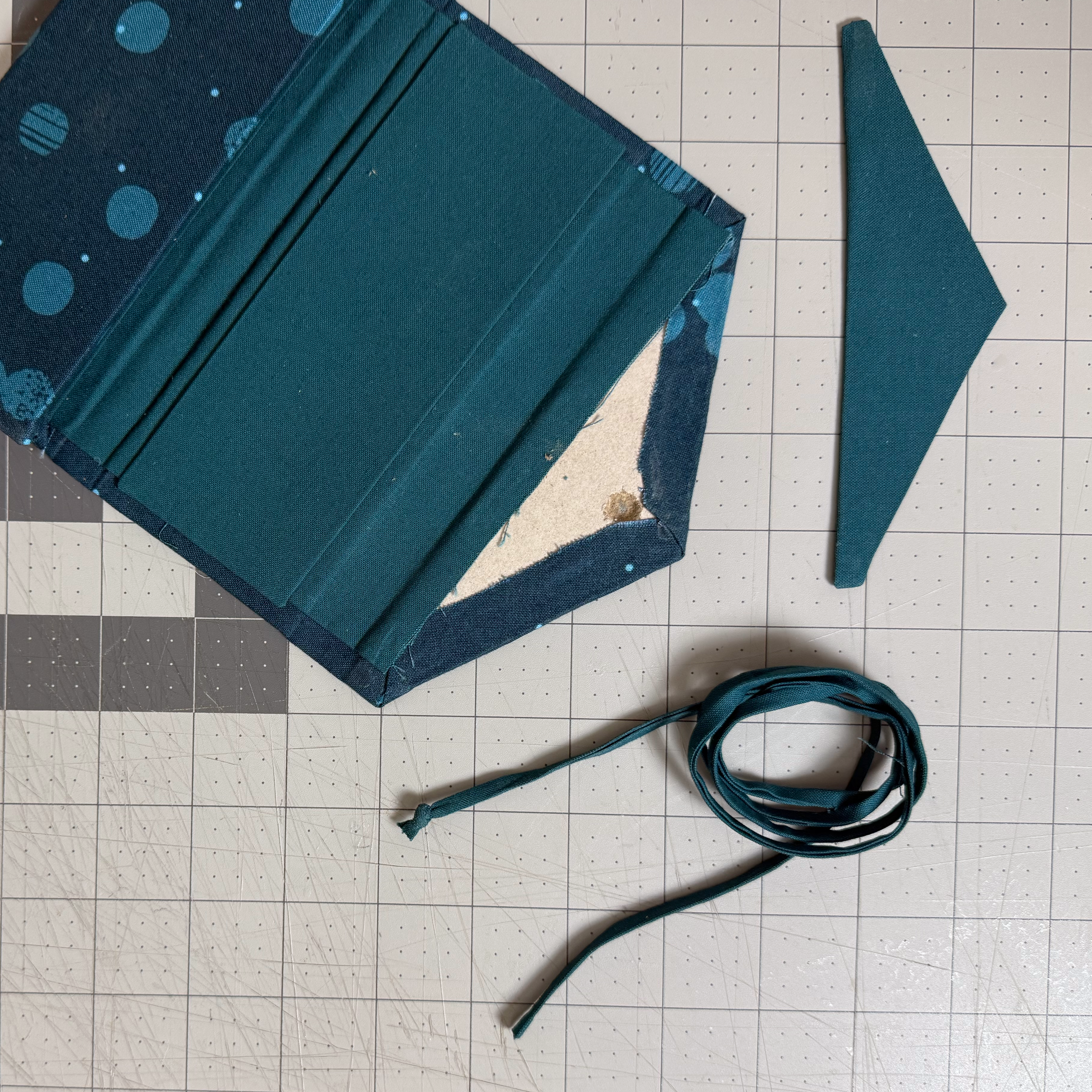 Knotted fabric tie beside its attachment hole and wrapped lining card