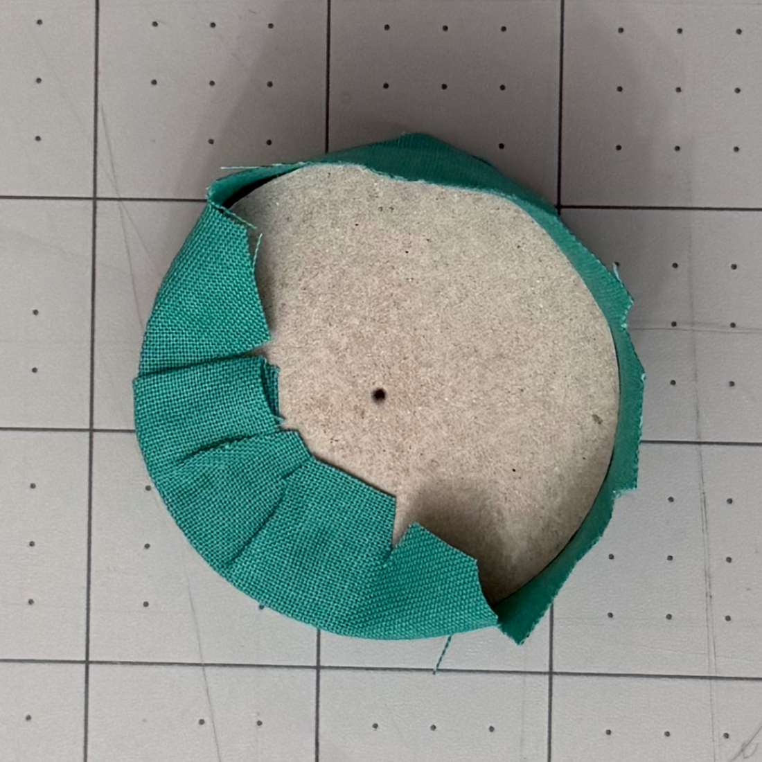 Fabric tabs being folded onto the back of a chipboard circle